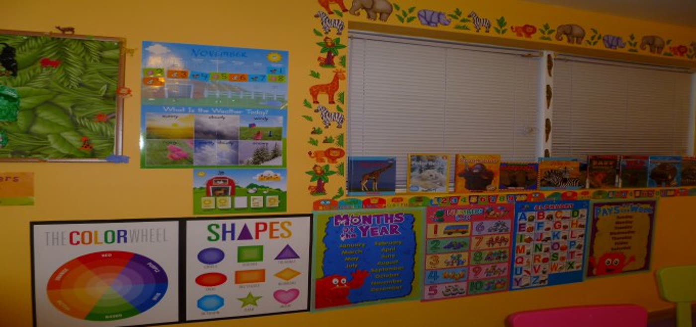 A wall of alphabet, color, and shape learning posters in the Little Bird classroom corner