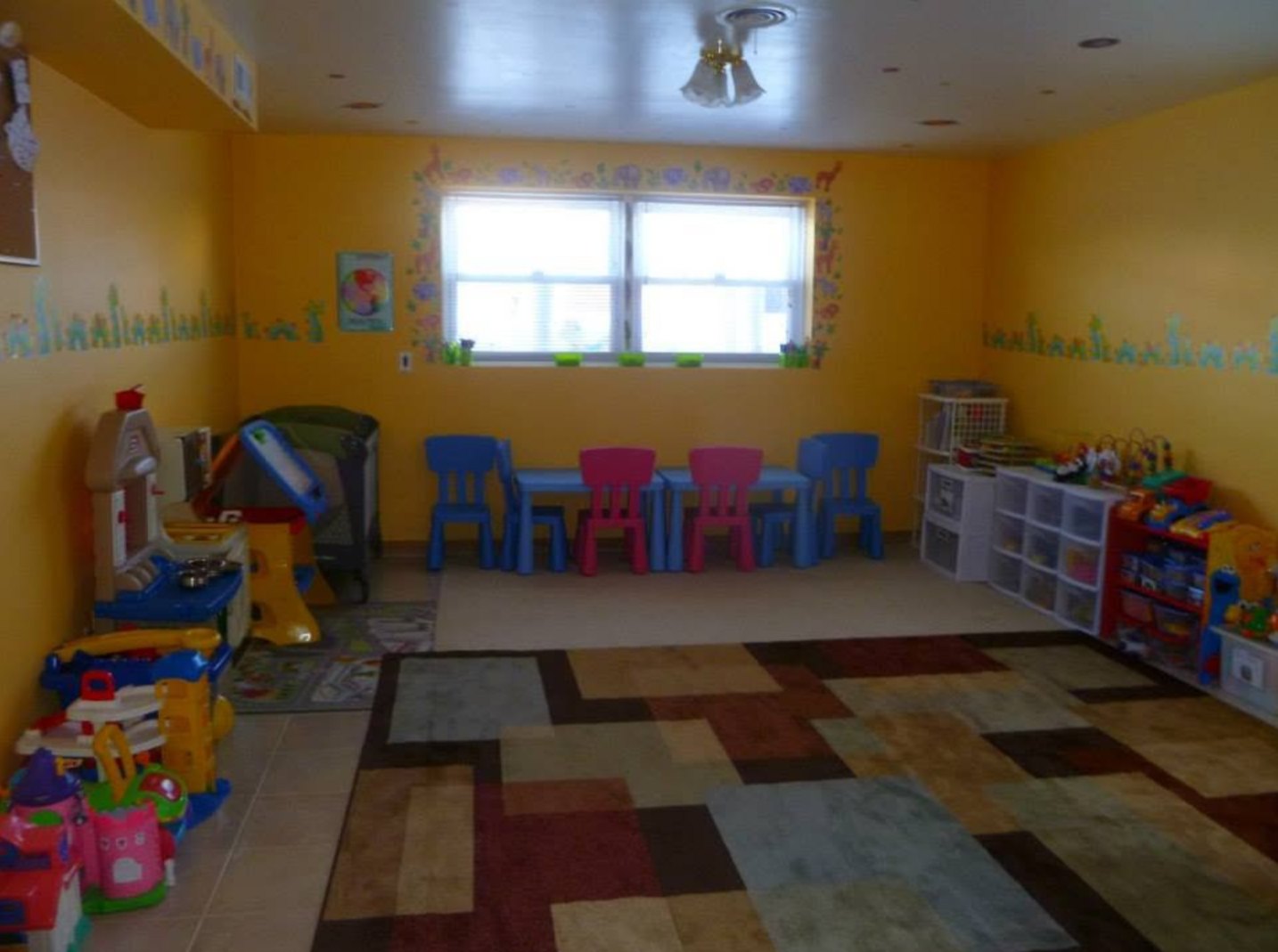 A colorful playroom with a play kitchen, little table and chairs, and toys